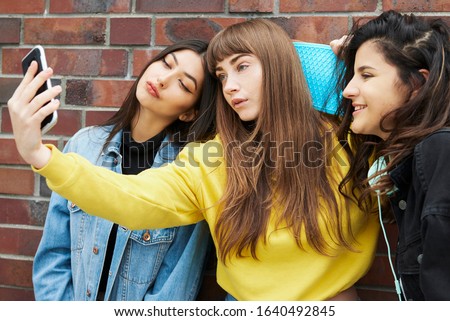 Three girls making a selfie by mobile phone 