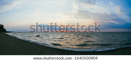 A lonely fishing boat in the sea against the background of the evening sunset sky. Large panorama