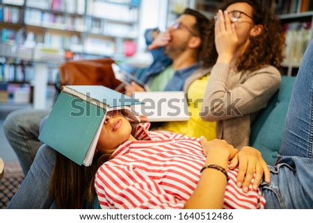 College, study, university and education concept. Group of tired students learning in library