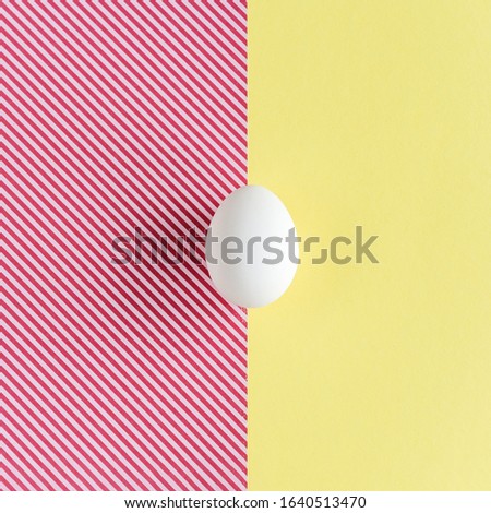 White egg on a yellow and red striped background. Minimalism concept

