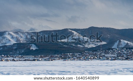 Landscape Russian village covered by snow. Winter landscape with simple wooden houses. Rural life in winter. Russia, Siberia, Altai Territory, Belokurikha.