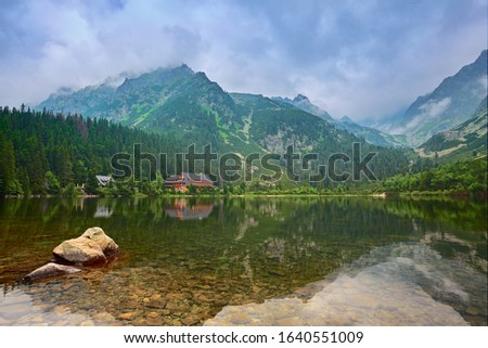 A clear and calm lake high in the mountains. Little house by the lake. A place for tourism and recreation. Popradske pleso, Slovakia, Europe. Beauty world.
