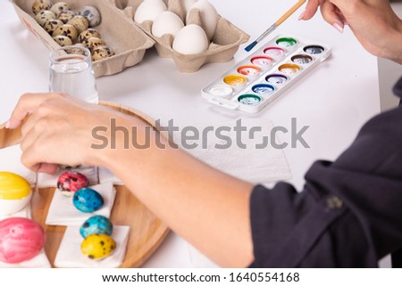 Easter, holidays, tradition and people concept - close up of woman hands coloring easter eggs with brush