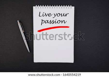 Notebook with the inscription Live Your Passion on a black table.