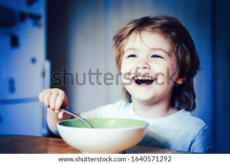 Kid eating. Little boy having breakfast in the kitchen. Smiling happy adorable baby eating fruit mash in the kitchen. Hungry little boy eating