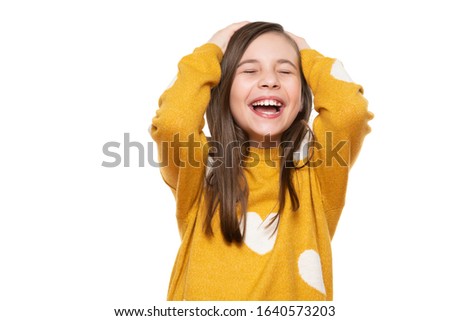 Waist up studio portrait of an adorable young girl laughing with excitement, head in hands and closed eyes, isolated on white backgroud. Human emotions and facial expressions concept. Royalty-Free Stock Photo #1640573203