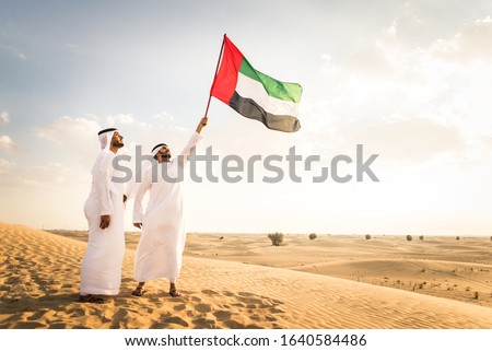 Arabian men witk kandora walking in the desert - Portrait of two middle eastern adults with traditional arabic dress Royalty-Free Stock Photo #1640584486