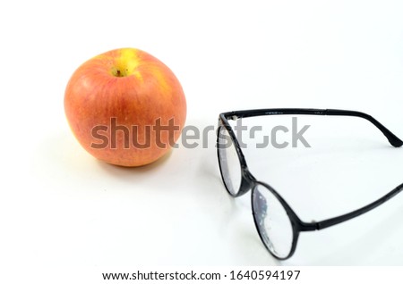Red apple and presbyopic glasses on white background