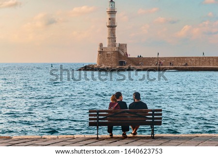 young couple in love sitting on a bench by the sea on the waterfront of the Greek city of Chania
