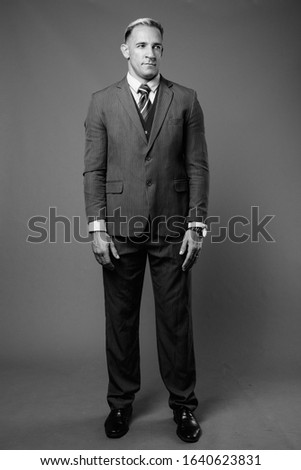 Full body shot of businessman in suit against gray background