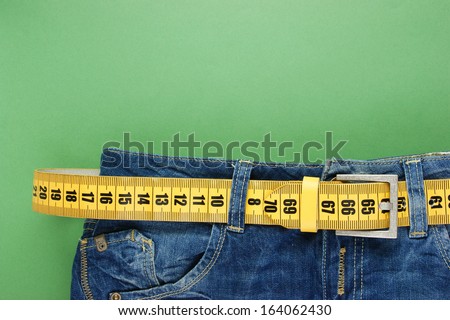jeans with meter belt slimming on the green background Royalty-Free Stock Photo #164062430