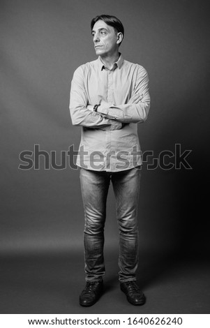 Mature handsome Italian man against gray background