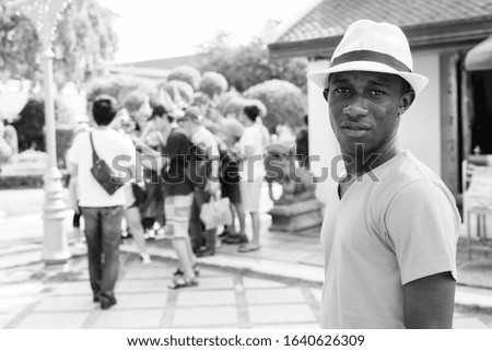 Young African tourist man with group of Asian tourists at Wat Arun temple