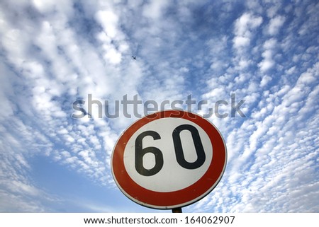 road sign speed limit sixty under cloudy blue sky
