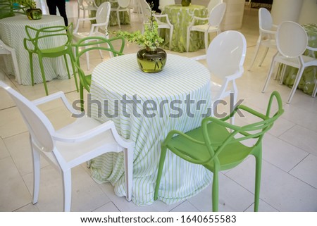 interior white table green chairs with vase and flowers out of focus and grain