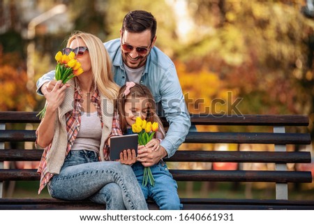 Happy family of three having fun together outdoor.Family,lifestyle and technology concept.Spring day in the park.