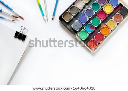 Watercolor paintbox and brushes on white background. Flat lay, top view
