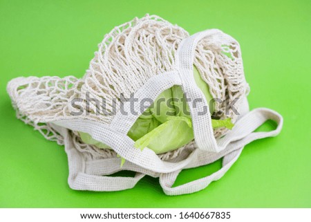 string bag with cabbage and courgette on green background