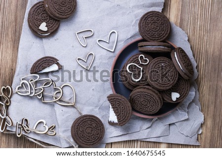 chocolate chip cookie sandwich in a clay plate on kraft paper on a wooden background. hearts of wood. Happy Valentine's day. beautiful picture with biscuits. texture.