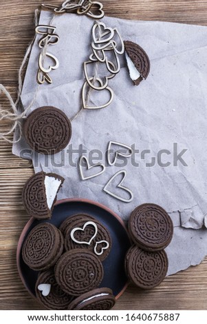 chocolate chip cookie sandwich in a clay plate on kraft paper on a wooden background. hearts of wood. Happy Valentine's day. beautiful picture with biscuits. texture.