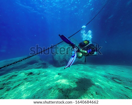 Diver sailing along the anchor at the bottom of the Mediterranean Sea