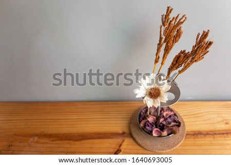 Home interior decor in grey walls and the  wood table : stainless vase with dried flower, Living room decoration. Rustic still life.