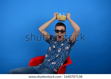 Crazy man in 3D glasses with popcorn on his head on a blue background