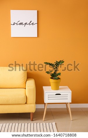 Interior of modern room with comfortable armchair and table near color wall