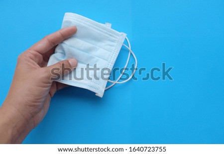 close up woman hand holding Medical and protective face mask isolated on blue background