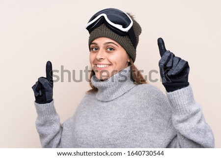 Teenager skier girl with snowboarding glasses over isolated background pointing up a great idea