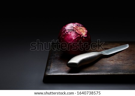 Red onion with a stainless steel knife food setup with high contrast light to create mood, Fine art