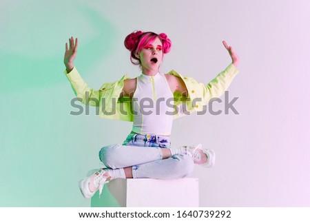 young woman in bright youth clothes sits on a white pedestal