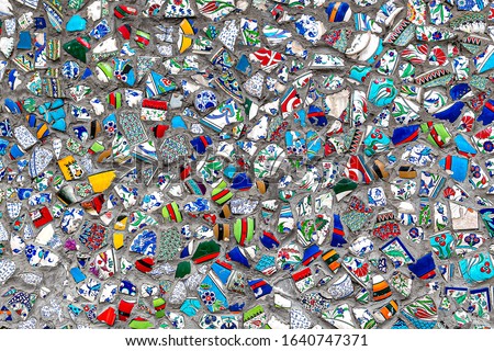 Decorative wall decorated with ceramic fragments of broken earthenware dishes attached with a concrete solution. Background image