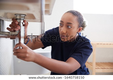 Female Plumber Working To Fix Leaking Sink In Home Bathroom Royalty-Free Stock Photo #1640758150