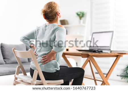 Woman working on a laptop and having back, hip, spine pain. Royalty-Free Stock Photo #1640767723