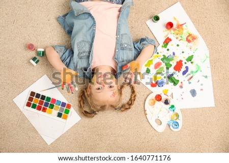 Cute little child with painted face and palms on floor, top view