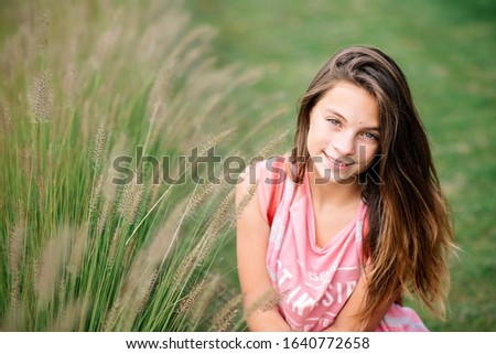 Portrait of a beautiful young girl in green summer grass. Soft selective focus.