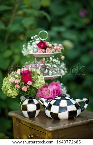 Alice in Wonderland. Scenery for a fairy tale. teapot cups flowers in a vase on a table in a green forest. vertical