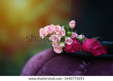 Alice in Wonderland. Hat cylinder decorated with flowers roses. Soft selective focus.