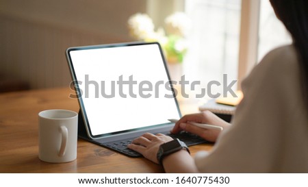Young business women are using blank screen laptop with coffee cup in modern office.