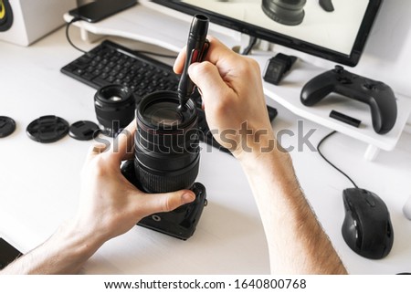 A man cleans the lens from dust and dirt with a special pencil.