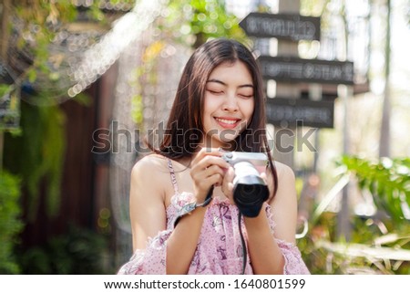 Cute girl with pink dress holding a camera closing her eyes and smiling