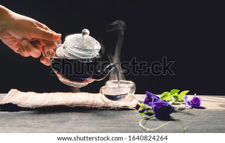 The steam from a cup or pot of tea on the old wood table and black background with nature light by window in the morning, Warm drinks make good healthy, Selective focus.