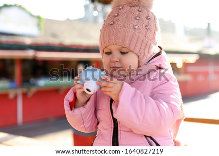 Cute little photographer with toy camera outdoors
