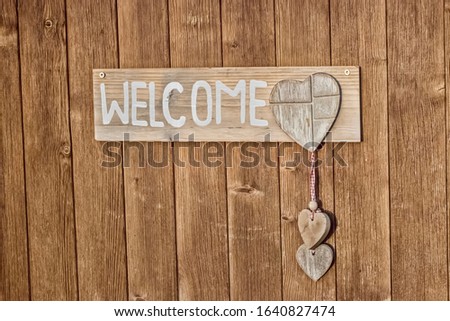 Welcome Plate made from wood on wood wall.