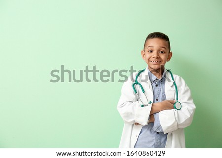 Cute little African-American doctor on color background Royalty-Free Stock Photo #1640860429