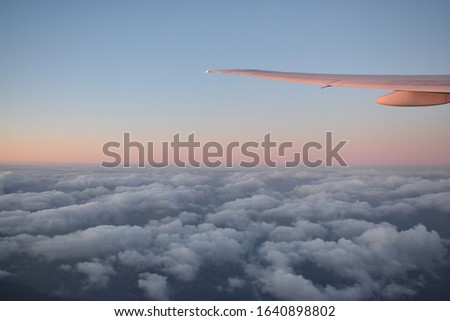 Beautiful clouds on the sky with dramatic sunset light under Aircraft wing, view from airplane window.
