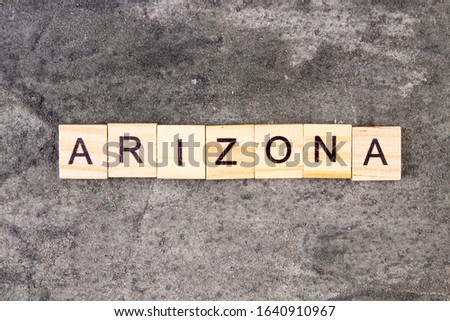 Arizona word written on wood block, on gray concrete background. Top view