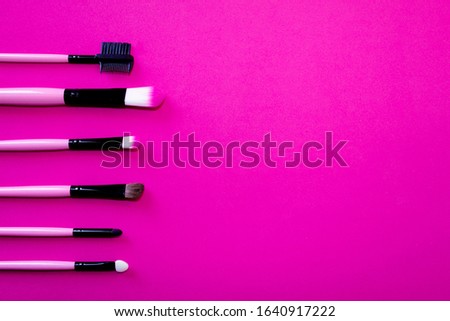 photography with pink magenta background with some makeup brushes on the side