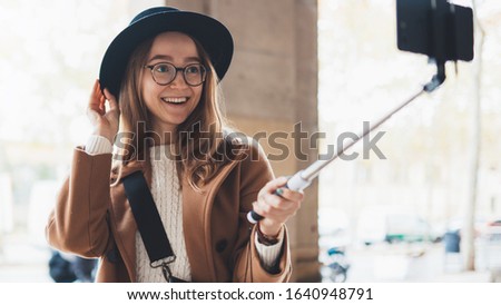 Smile traveler in glasses and hat self cellphone internet technology in europe trip. Tourist girl taking photo selfie on smartphone mobile. Blogger hipster travels inBarcelona. Holiday concept